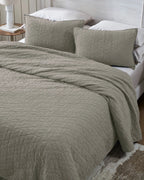 Stone organic tri-color stitch hand quilt set with standard pillow covers, top view on a made bed