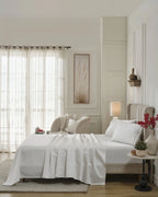Tofu 1000TC sateen flat and fitted sheet set with standard pillow covers, side view on a made bed