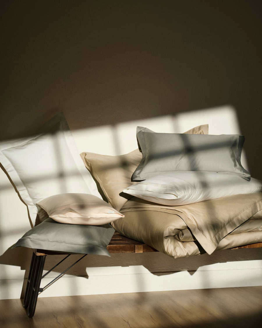 Neutral-toned sheets and pillows on a daybed in soft window light